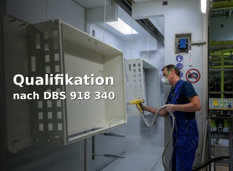 Pulverbeschichtung in der Kabine: Mitarbeiter sprüht Bauteil; links Text ‚Qualifikation – nach DBS 918 340‘.