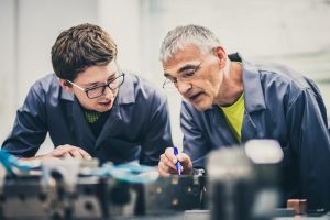 Senior engineer explaining machine functioning to his student Ingenieur Maschinenbau